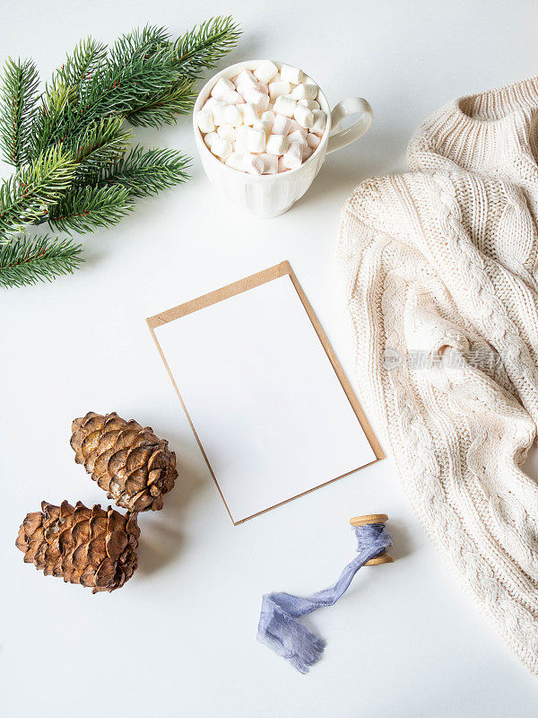 白色马克杯，热饮和棉花糖，纸卡的信件，信封和圣诞装饰在白色的背景。前视图。本空间