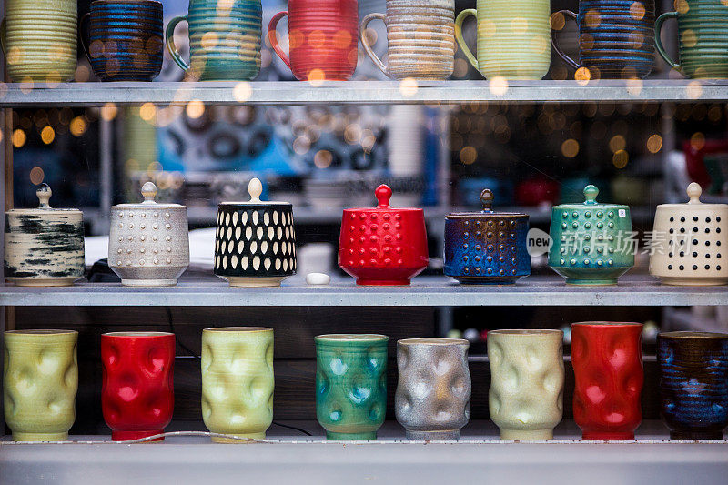 手工制作的彩色陶瓷咖啡杯和壶排成一排展示