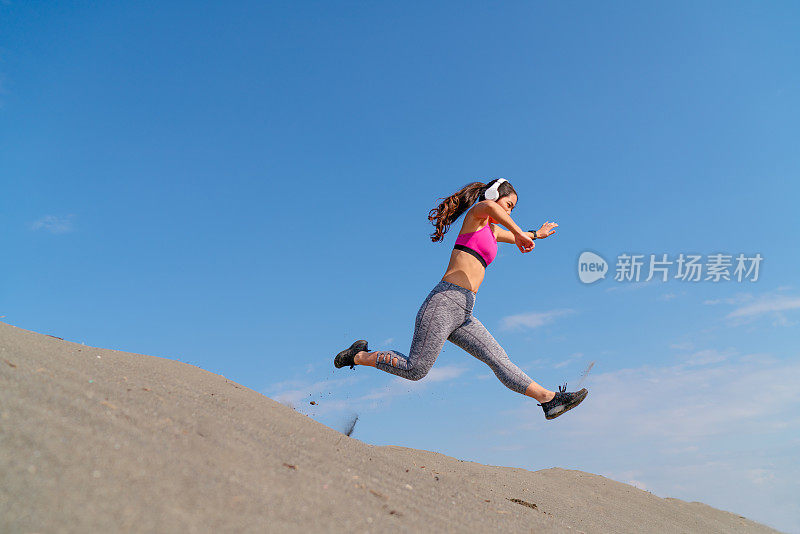 女运动员在沙滩上跑下山