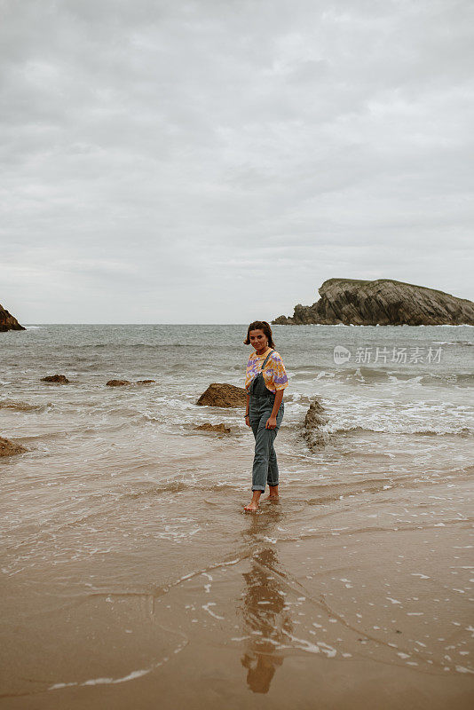 一个年轻的女人在海滩上散步和玩乐