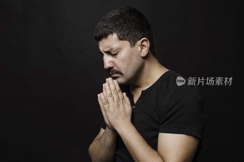 祈祷的男人肖像在黑色的背景