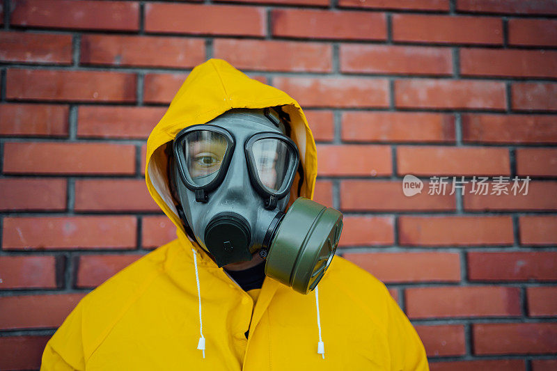 一个穿着防护服戴着防毒面具的人站在一堵墙前