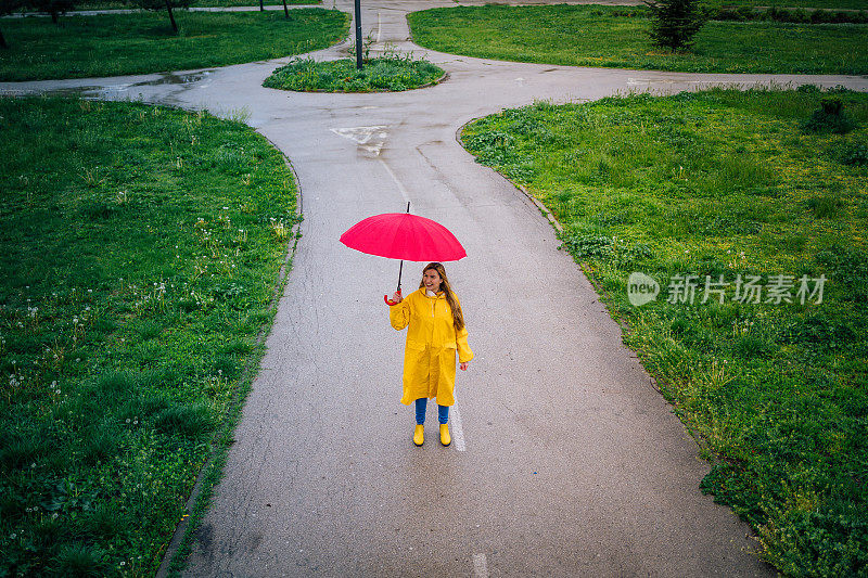 一个女人撑着一把红伞在雨中行走