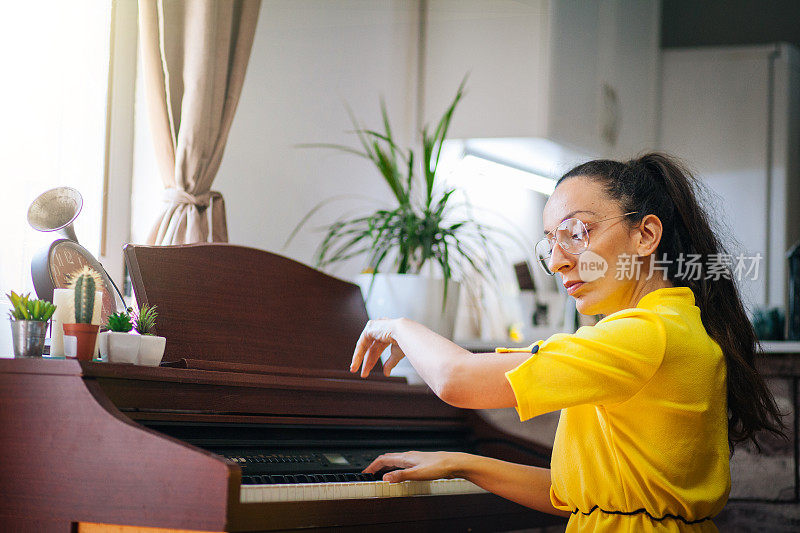 年轻的女钢琴家在自己家里的房间里谱曲