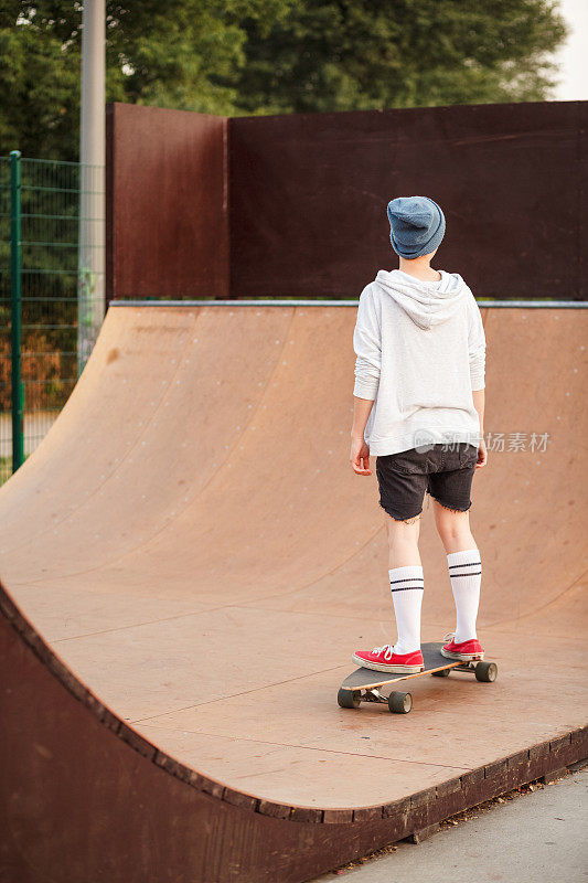 复制空间拍摄的一个十几岁的女孩溜冰在她的滑板运动坡道