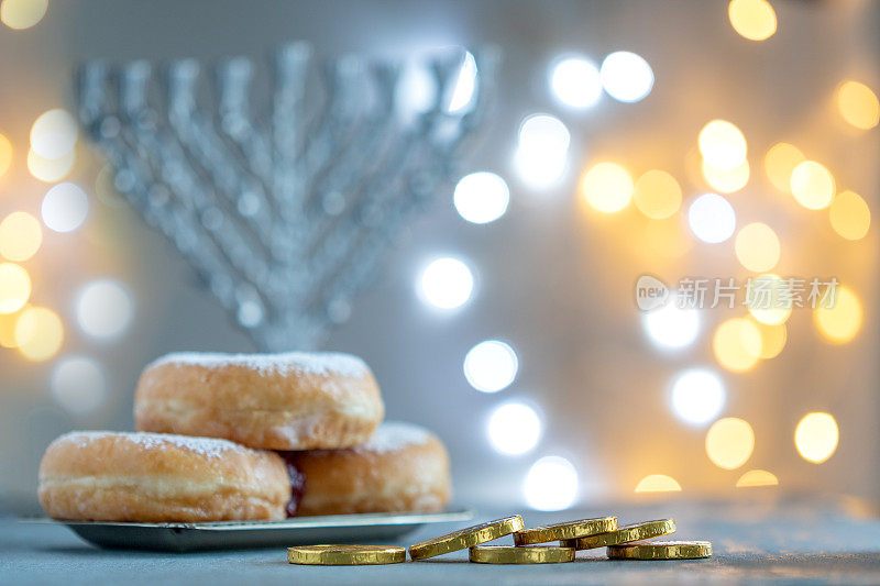 光明节的概念与烛台，sufganiyah，木制陀螺，巧克力硬币和明亮的灯光在背景