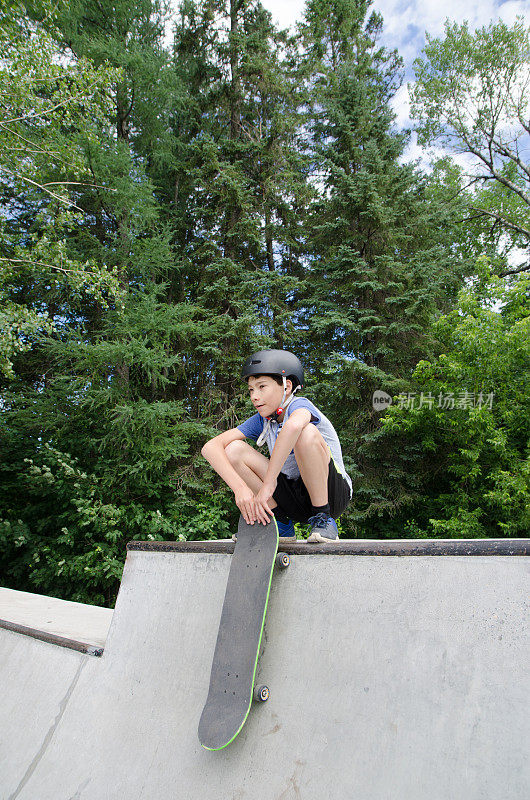 一个小男孩在坡道顶上玩滑板
