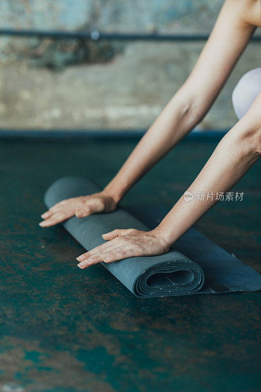 瑜伽在家里:一个匿名女人的手展开她的练习垫在地板上，一个近距离