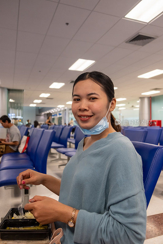 一个泰国女孩在等飞机的时候吃东西。
