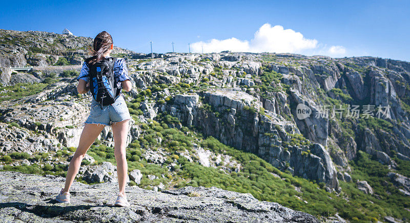 背着背包的年轻女子徒步旅行者在户外的山区旅行