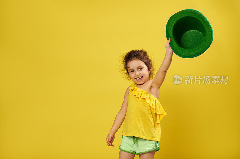 可爱的小女孩举起手，手里拿着一顶绿色的爱尔兰妖精帽子。圣帕特里克节的概念