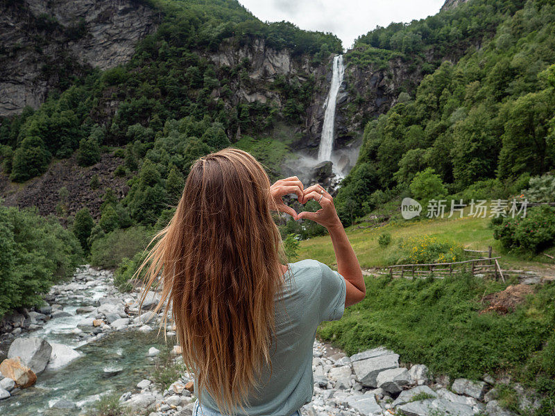 女人热爱自然，她用双手在瀑布上做了一颗心