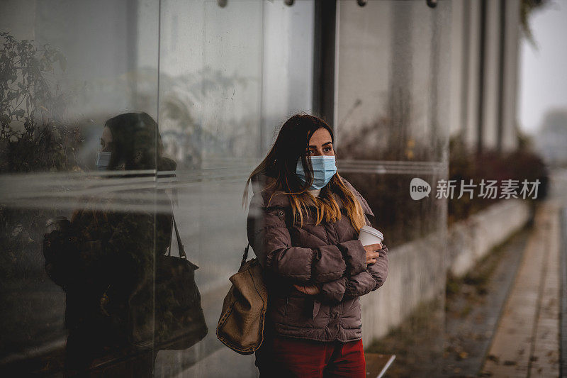 戴着防护面具等车的女人