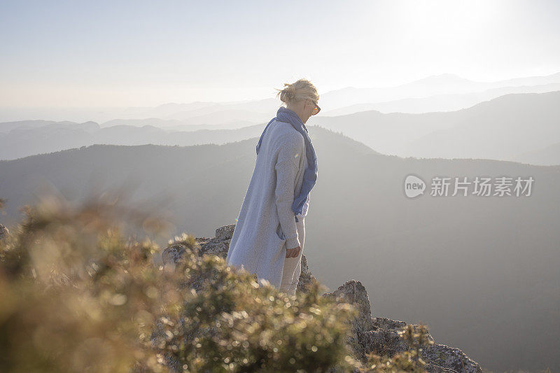 清晨，女徒步旅行者在阳光明媚的山脊上放松