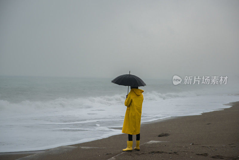 海滩上的风暴和穿着黄色雨衣的男人。暴风雨，暴雨，海岸，大浪