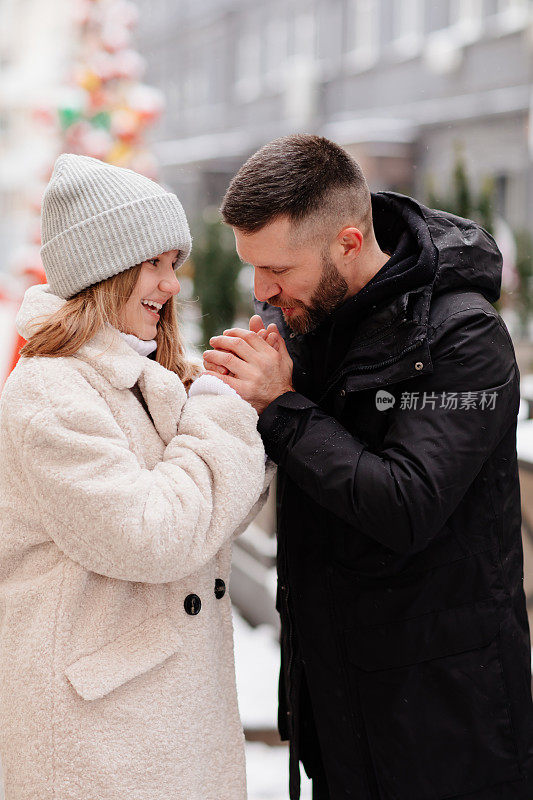 爸爸和女儿走在冬天的街道上，用呼吸温暖她的手。