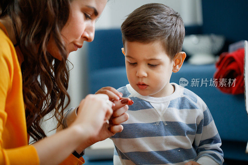 幼童和他的母亲专注于制作小的纸装饰品