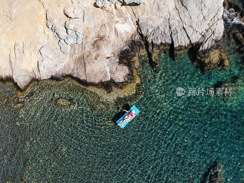 美丽的女人在海上的充气床垫上休息。