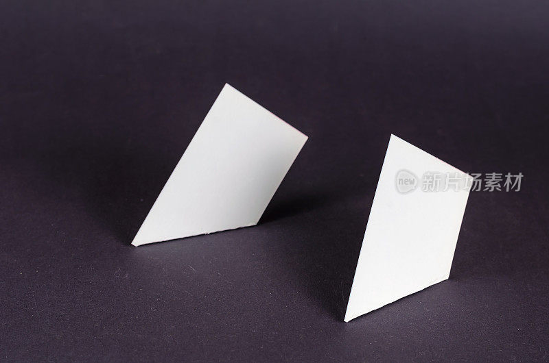灰色背景上的白色四边形的抽象几何构图。两个相似的几何形状，只有直角和锐角。