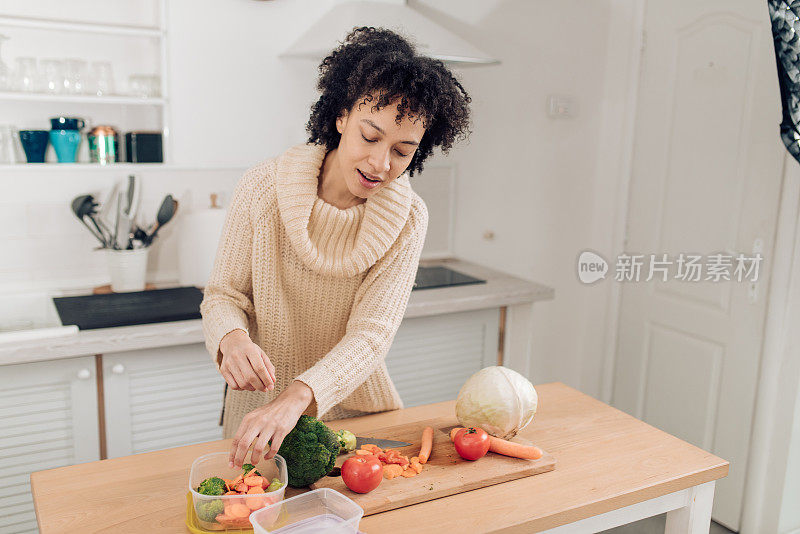 年轻的非裔美国妇女切蔬菜，然后装在PET盒子里