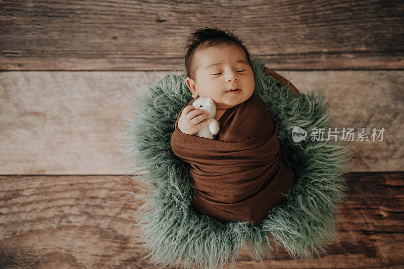 小男孩戴着编织的帽子，在篮子里快乐地睡觉