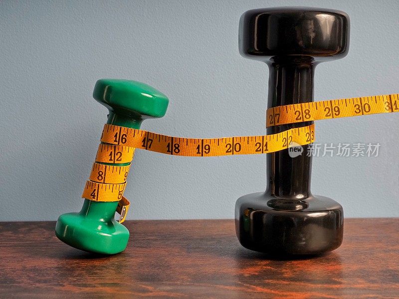 自由重量和卷尺，一个测量健身和减肥进展的概念形象