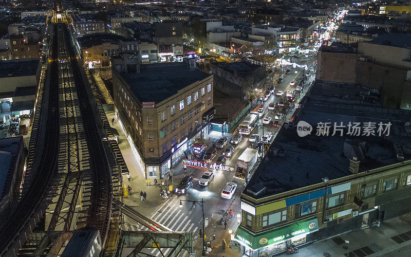 纽约布鲁克林布什威克的高架地铁和默特尔大道的鸟瞰图，在夜间照明。