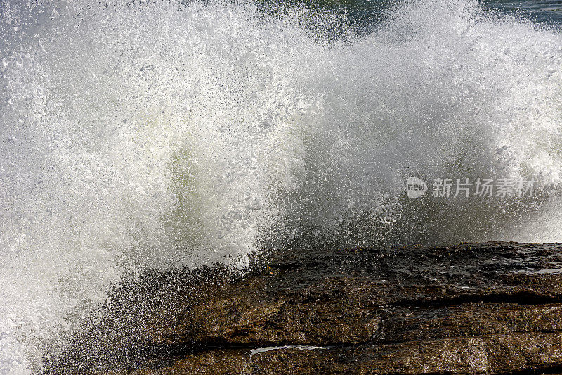 巨浪拍打岩石，水在空中飞溅