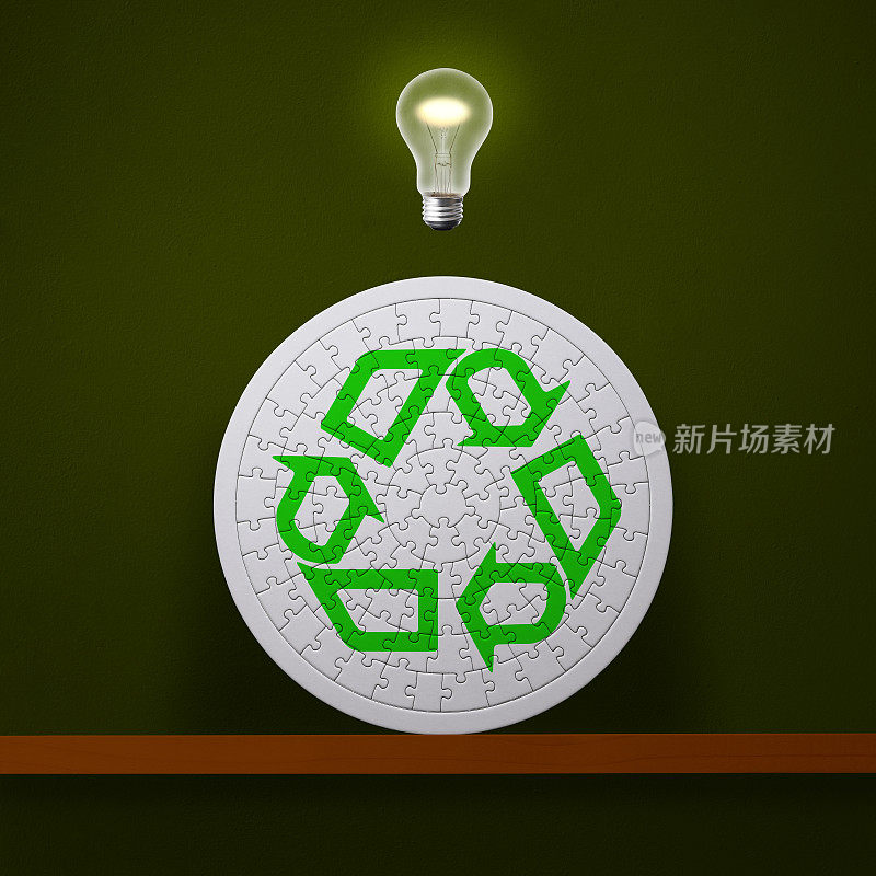 在木制架子上的绿色回收标志的拼图上方的半空中发光的灯泡