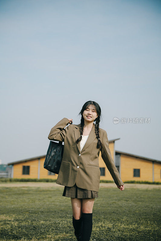 亚洲女大学生在阳光明媚的草地上快乐地玩耍