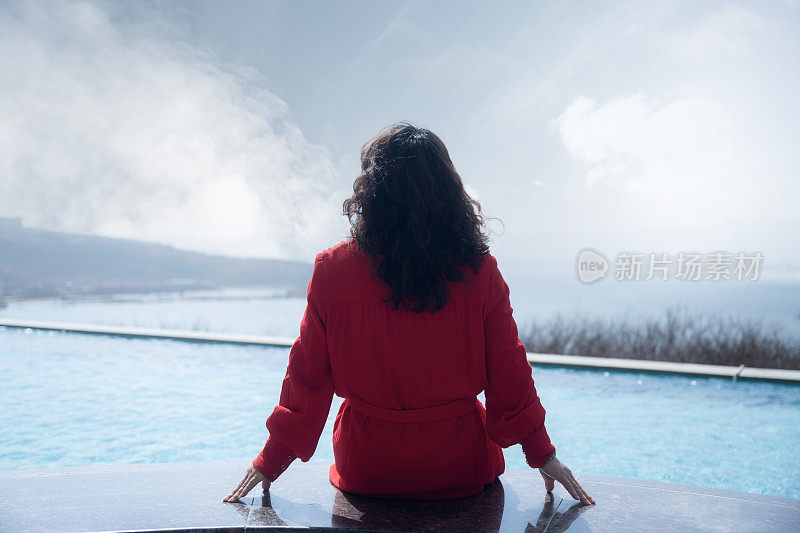 一个穿红衣服的女人坐在泳池边晒太阳