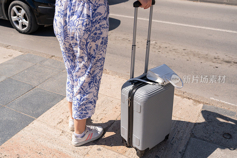 面目全非的女人提着行李箱在城里过马路