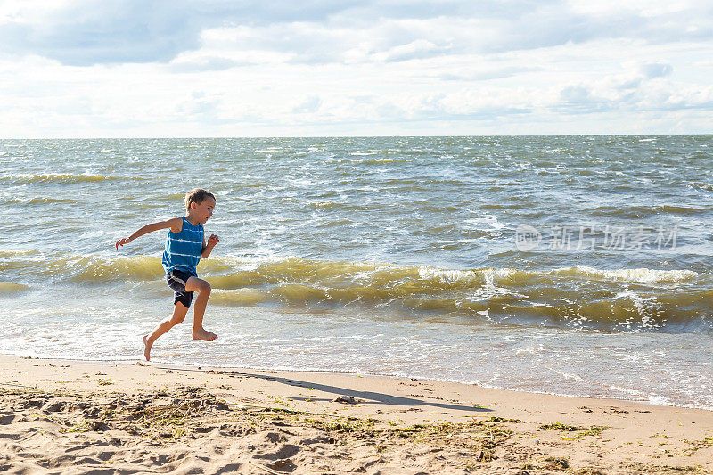 小男孩在Windy海滩冲浪