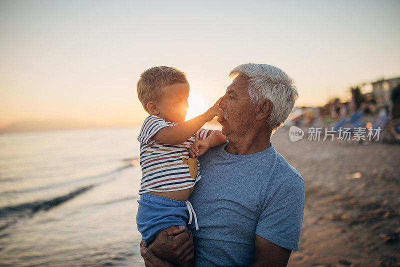 日落时分，爷爷和孙子在海滩上享受美好的一天