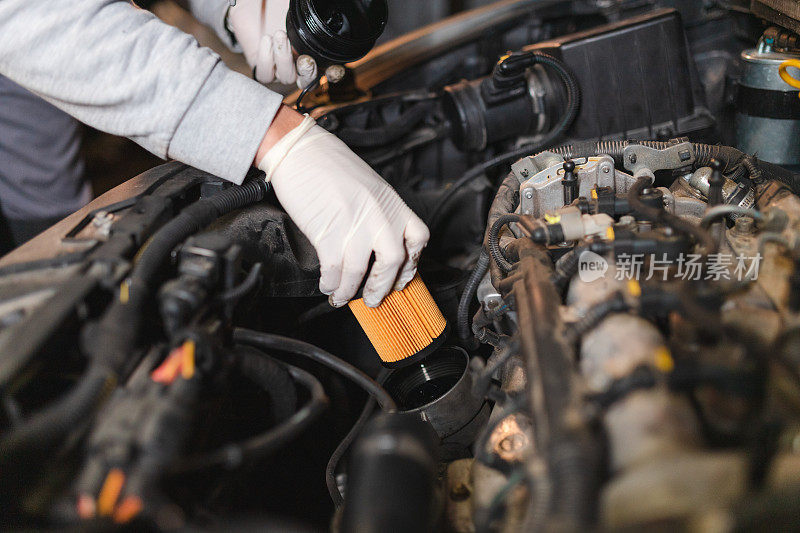 一个年轻的机械师在他的车库里安装一个新的机油过滤器的特写