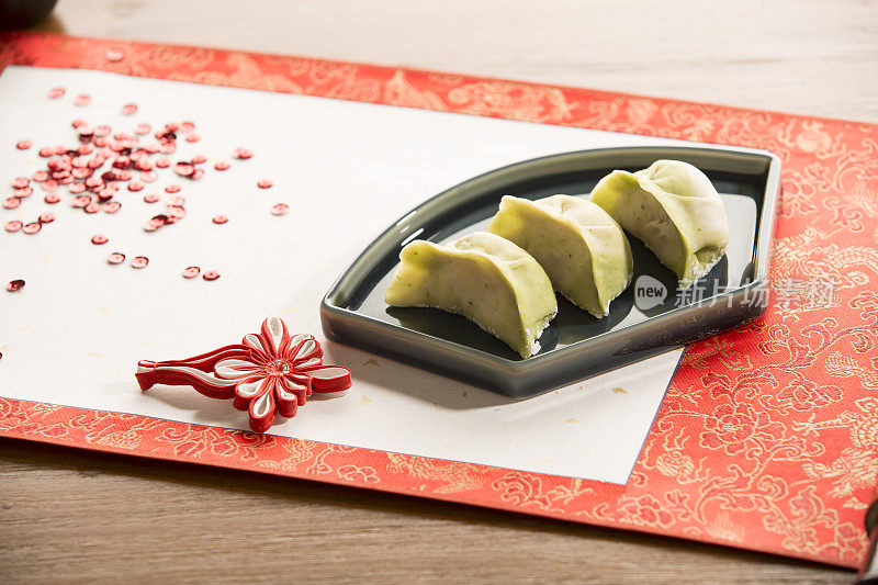 饺子，展开的书法画卷，中国结，中国新年，喜庆气氛背景