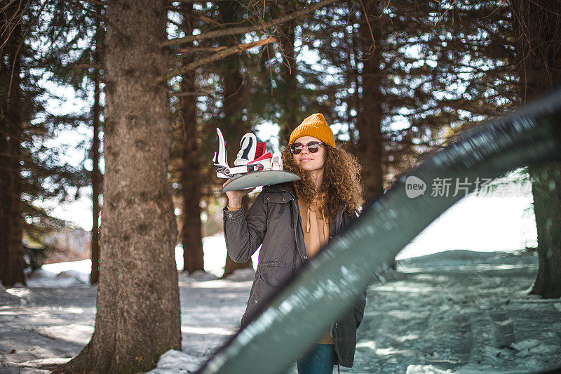 一个女孩在滑雪胜地的停车场拿着滑雪板摆姿势