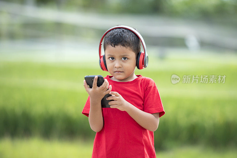 蹒跚学步的男孩用耳机听音乐