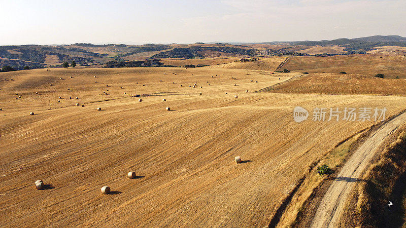 空中拍摄的农田，金色的草地和圆形的干草遍布