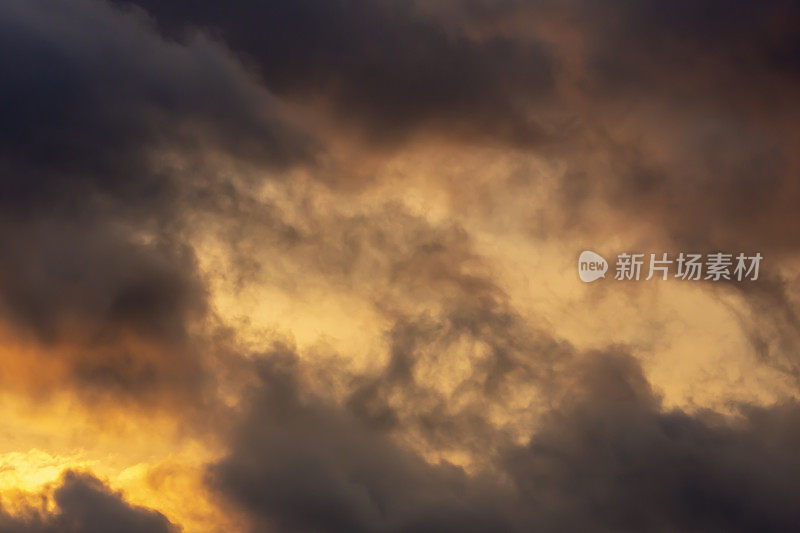 黎明多云的天空，画面左下方有一片明亮的橙色阳光