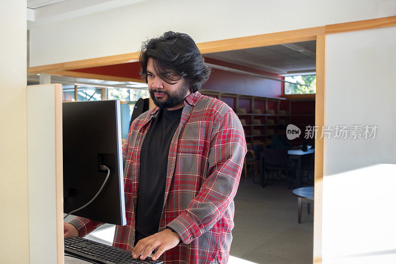 拉丁裔青年在图书馆使用公共电脑