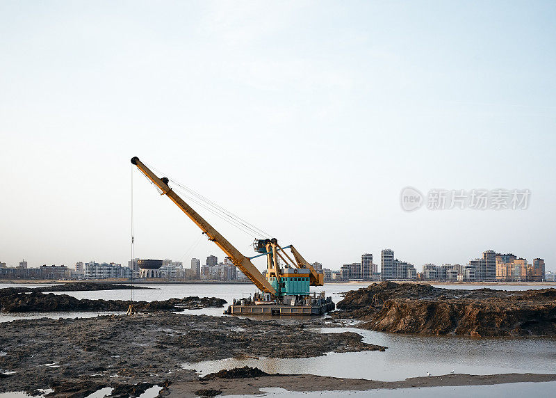 河岸边的挖掘机在海滩上挖掘淤泥