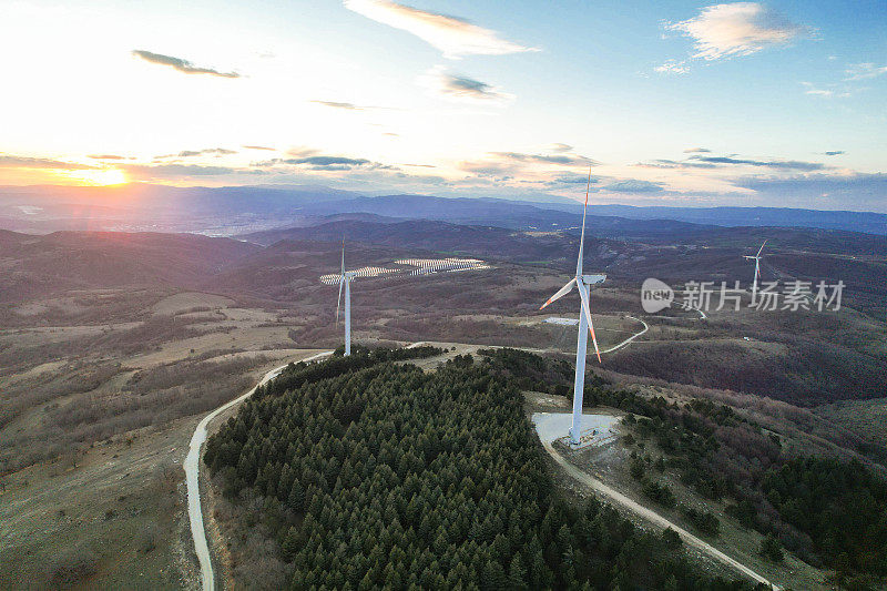 日落时的太阳能电池板和风力涡轮机。可再生能源