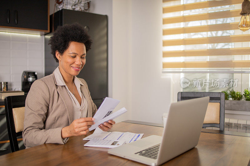 成熟的女人在计算账单和家庭财务时使用计算器