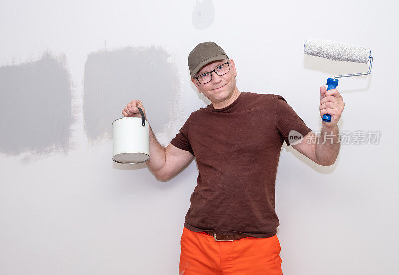 建筑工人是一名白人男子，手里拿着一个油漆滚筒和一罐油漆