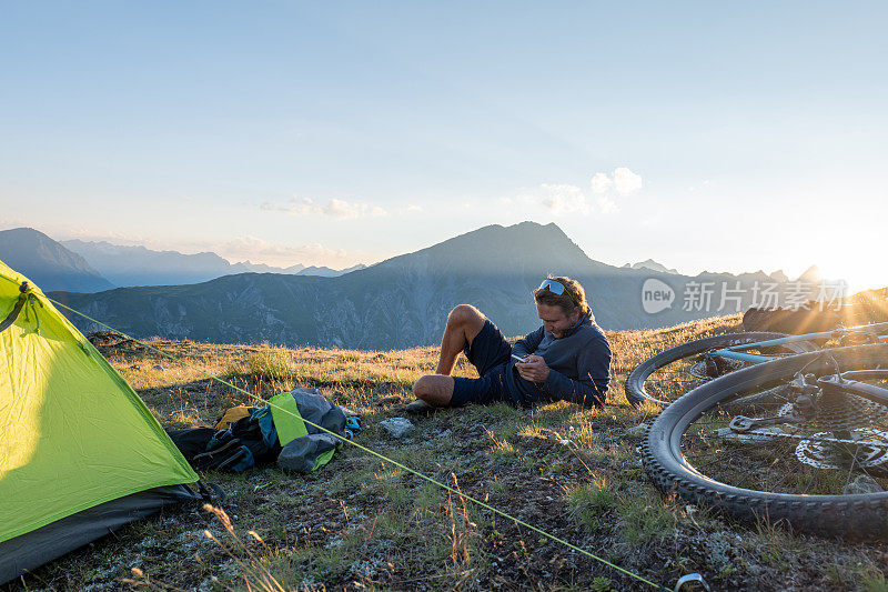 他在背包旅行和露营时，会在帐篷旁放松，并使用手机