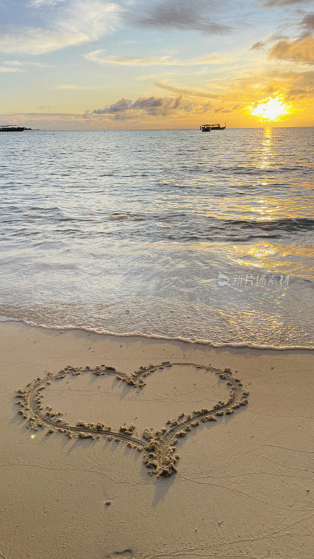 心的符号在夕阳下海边的沙滩上