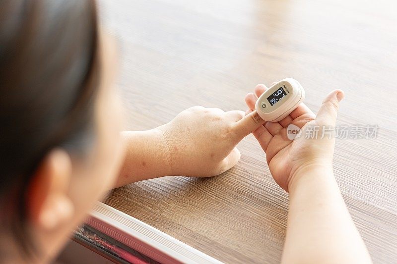 女性在粉色背景上使用指尖脉搏血氧仪，特写