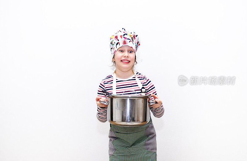 一个8岁的白人女孩，打扮成厨师，手里拿着一个大炖锅，面带微笑。情感的脸。