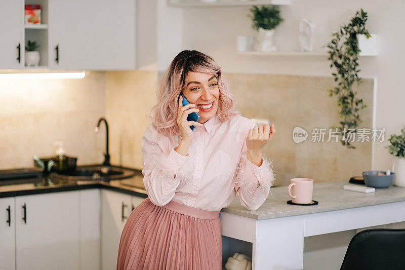 粉色头发的现代时尚女性，在厨房用手机